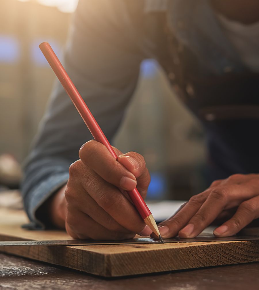 Tischler zeichnet Holz an mit einem Bleistift